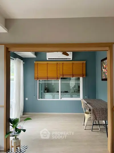 Spacious living room with modern decor and large window, featuring a stylish dining area and air conditioning.