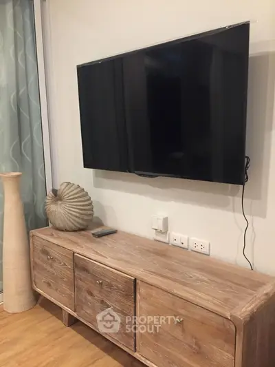 Modern living room with wall-mounted TV and rustic wooden console table.