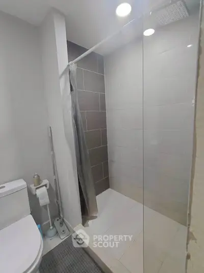 Modern bathroom with sleek shower and toilet, featuring contemporary tiles and bright lighting.