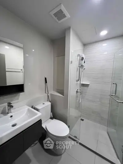 Modern bathroom with sleek fixtures and glass shower enclosure in a contemporary apartment.