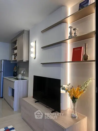 Modern living room with sleek shelving and stylish decor, featuring a compact kitchen area and elegant lighting.