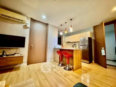 Modern open-layout kitchen and living area with stylish lighting and wooden flooring.