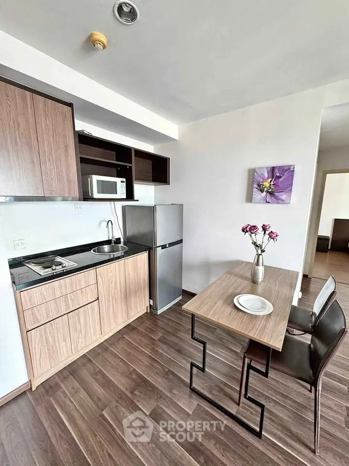 Modern compact kitchen with sleek wooden cabinets and dining area