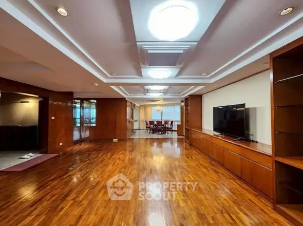 Spacious living room with wooden floors and modern lighting, perfect for entertaining.