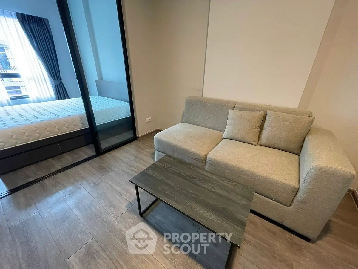 Modern living room with cozy sofa and glass partition to bedroom