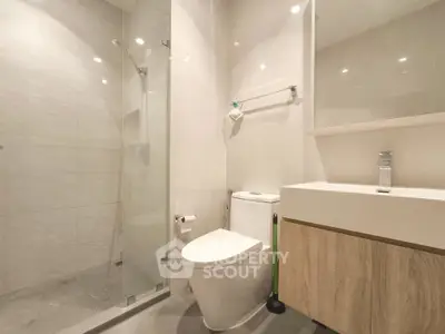 Modern bathroom with glass shower and sleek fixtures in contemporary apartment.