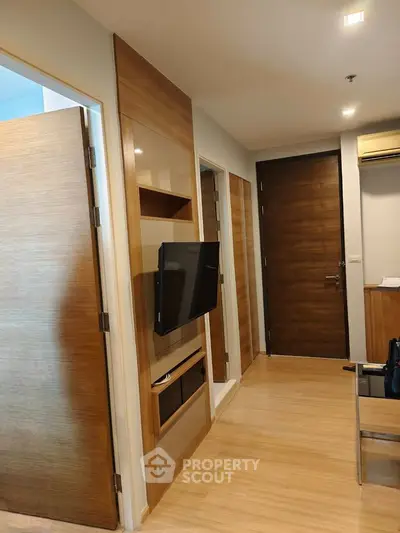 Modern apartment interior with wooden flooring and wall-mounted TV, showcasing sleek design and cozy ambiance.