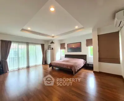 Spacious bedroom with wooden flooring and large windows in modern home