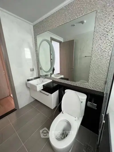 Modern bathroom with sleek fixtures and large mirror in a contemporary apartment.