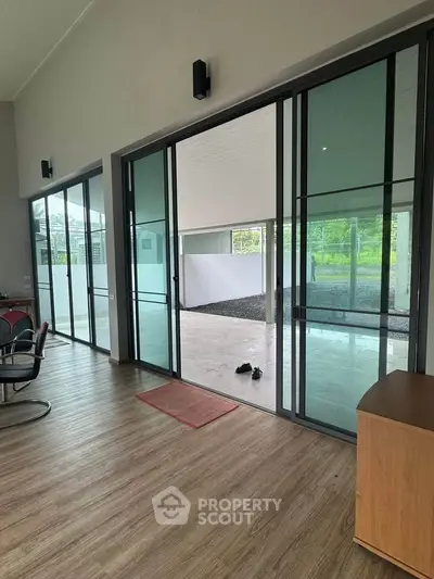 Spacious modern interior with large sliding glass doors opening to a patio, featuring sleek flooring and ample natural light.