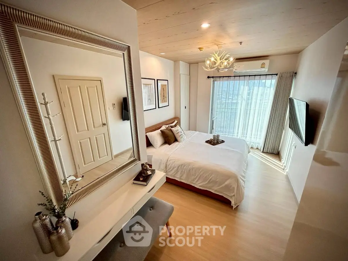 Modern bedroom with stylish decor, large mirror, and natural light from window.