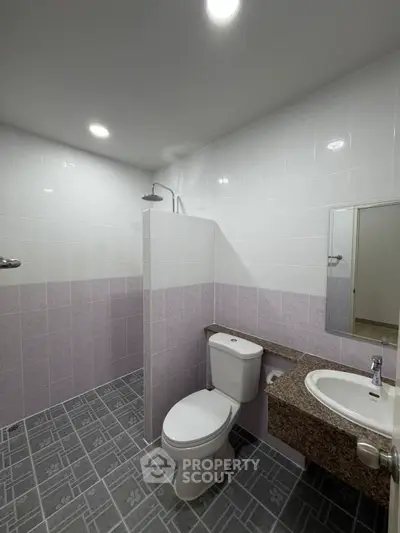 Modern bathroom with tiled walls and floor, featuring a shower and toilet.