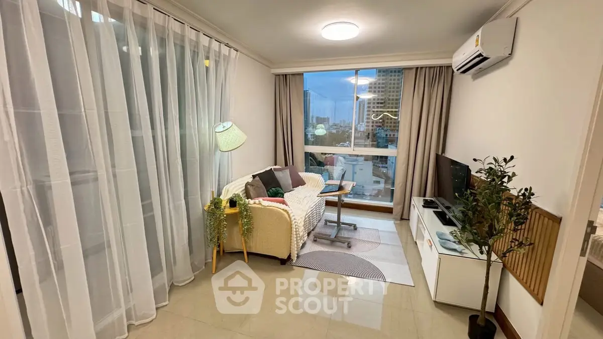 Cozy living room with modern decor and city view, featuring a comfortable sofa and entertainment unit.