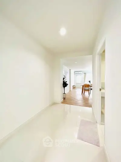Bright hallway leading to a modern living area with elegant decor and wooden flooring.