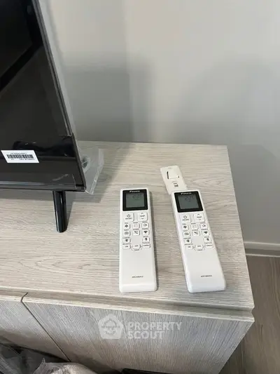 Modern living room with sleek TV and stylish remote controls on a wooden cabinet.