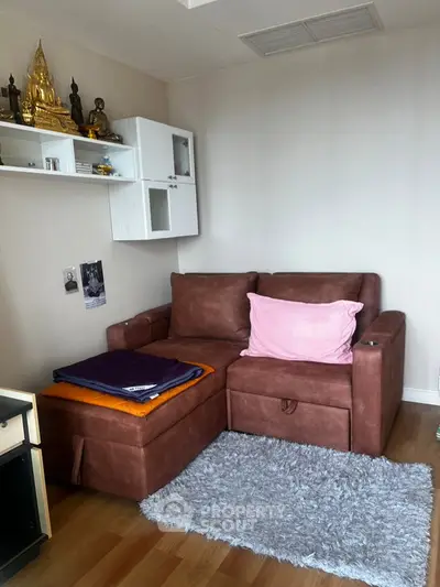 Cozy living room with brown sofa, decorative shelf, and soft rug