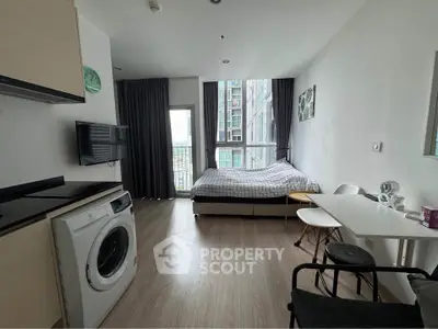 Modern studio apartment with washing machine and cozy bed, featuring a balcony view.