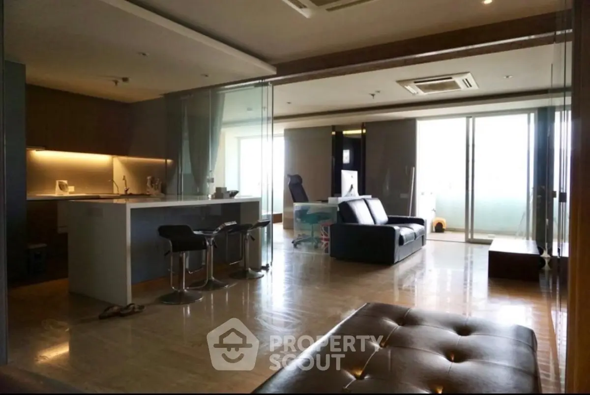 Spacious modern living room with open kitchen and large windows offering natural light.