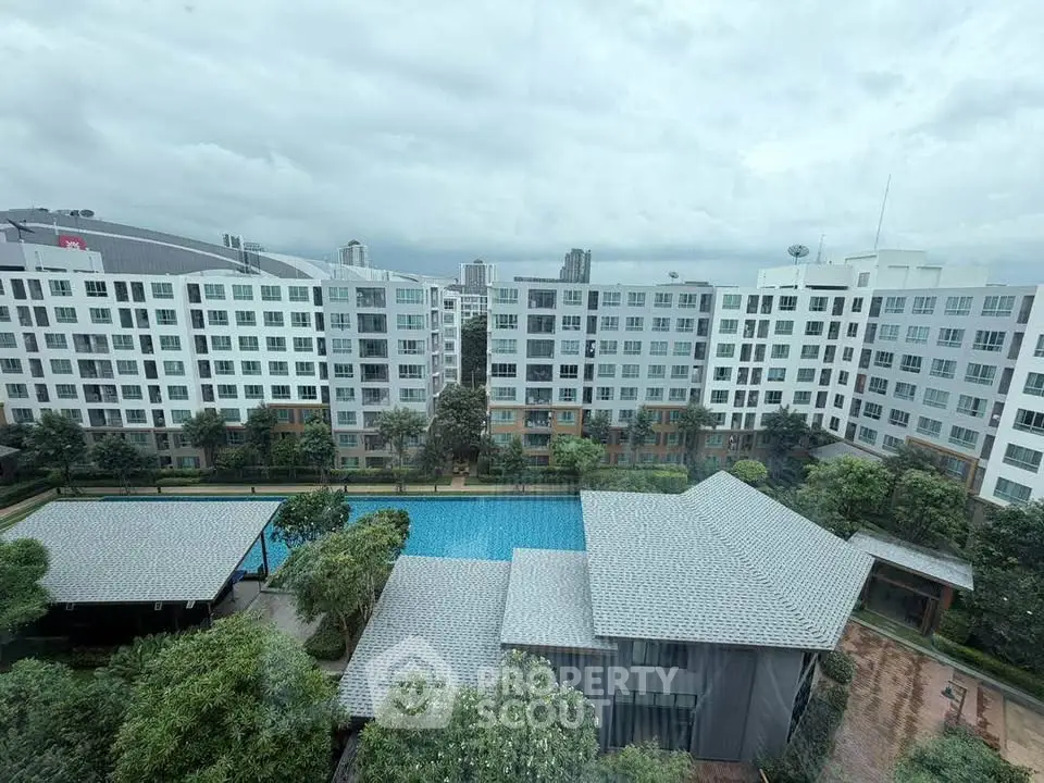 Stunning view of modern apartment complex with pool and lush greenery, perfect for urban living.