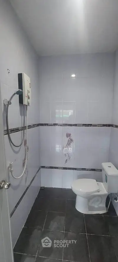 Modern bathroom with sleek tiles and water heater, perfect for a cozy home.