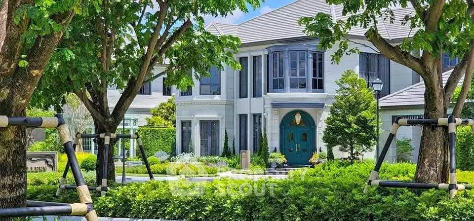 Luxurious two-story mansion with lush garden and elegant entrance