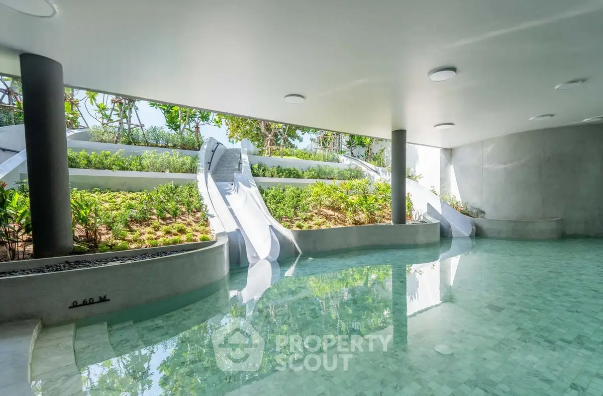 Luxurious indoor pool with water slides and lush greenery, perfect for relaxation and entertainment.