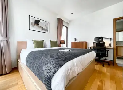 Modern bedroom with stylish decor and workspace, featuring a cozy bed and natural light.