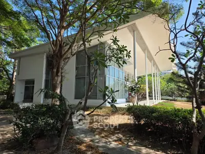 Modern architectural home with large windows and lush garden surroundings, offering serene and stylish living.