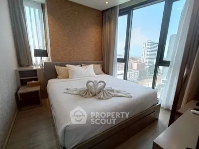 Modern bedroom with large windows and city view, featuring elegant decor and cozy ambiance.