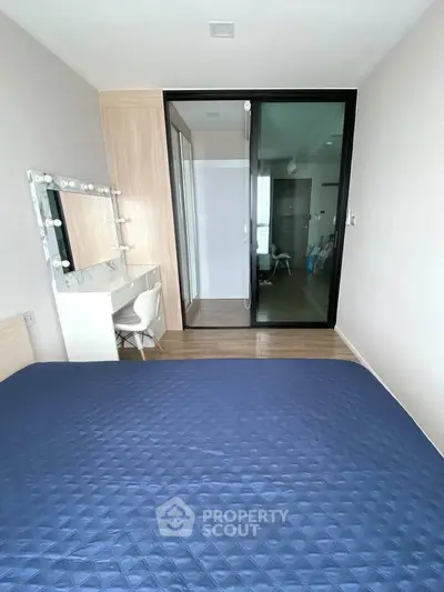 Modern bedroom with stylish vanity and glass sliding door in a contemporary apartment.
