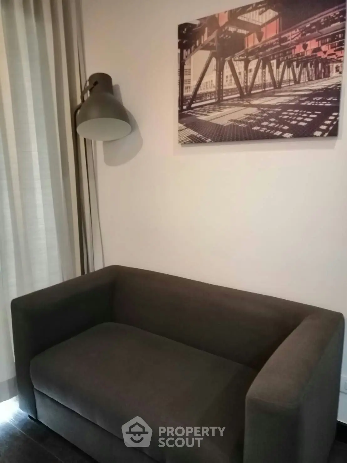 Modern living room with stylish gray sofa and industrial artwork, perfect for urban living.