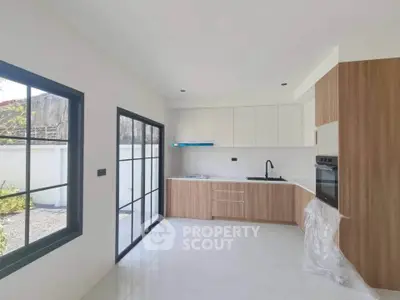 Modern kitchen with sleek cabinetry and large windows in a bright, open space.