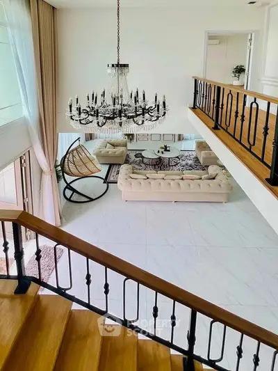 Luxurious living room with elegant chandelier and stylish decor in a modern duplex apartment.