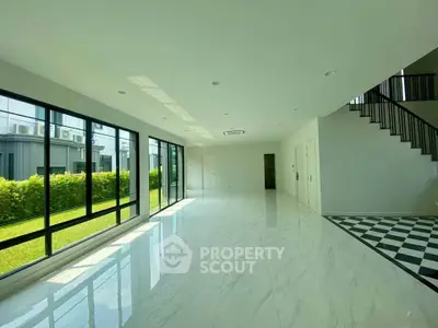 Spacious modern living room with large windows and marble flooring, offering abundant natural light and garden view.