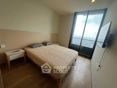 Modern bedroom with large window and city view, featuring a cozy bed and wall-mounted TV.