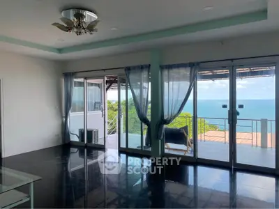 Spacious living room with ocean view and large glass doors opening to balcony.