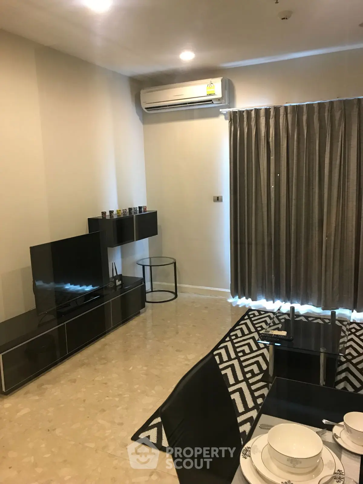 Modern living room with sleek furniture and dining area, featuring air conditioning and stylish decor.