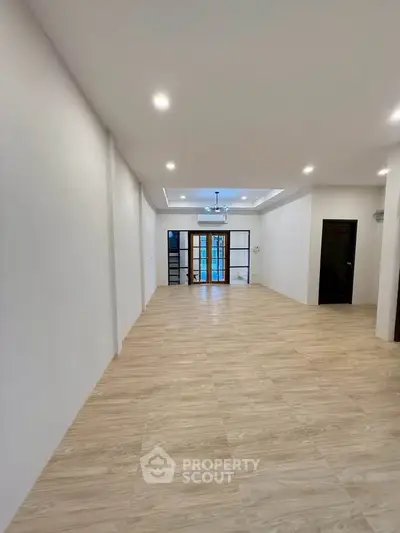 Spacious open-plan living room with elegant wooden flooring and modern lighting.