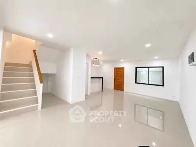 Spacious modern living room with sleek tile flooring and staircase, ideal for contemporary living.