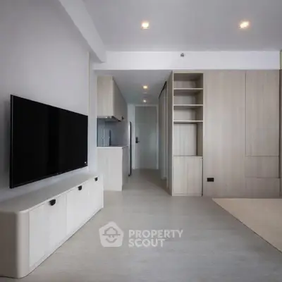 Modern minimalist living room with sleek TV setup and ample storage space.