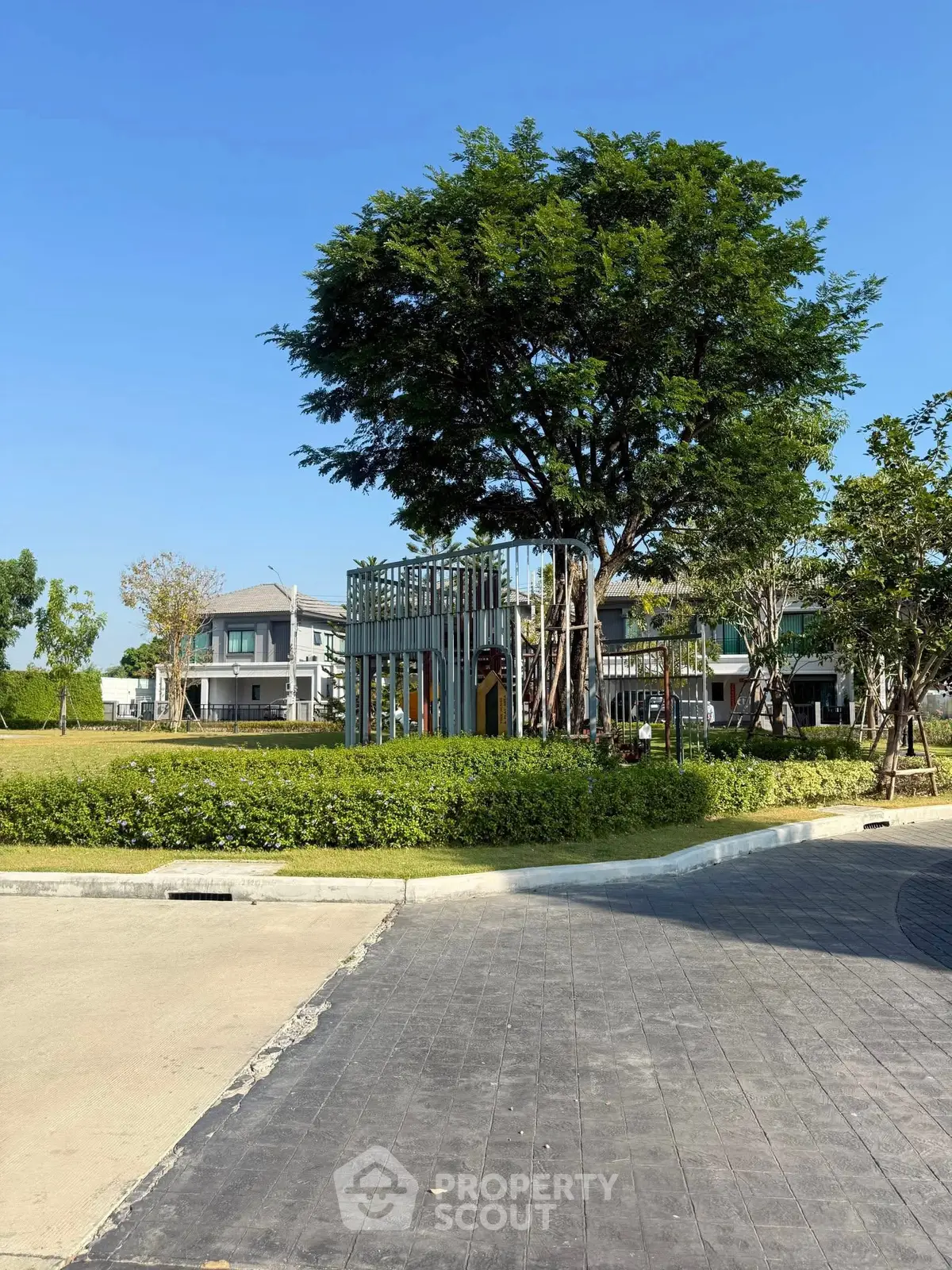 Charming residential area with lush greenery and modern homes under a clear blue sky.