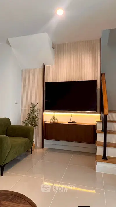 Modern living room with sleek TV setup and stylish staircase