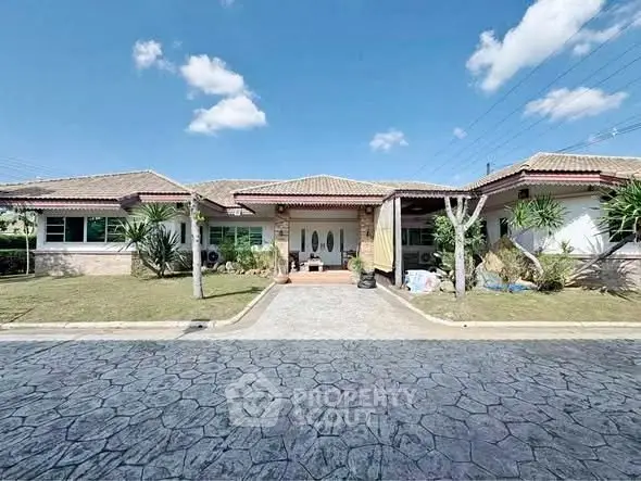 Charming single-story home with spacious driveway and lush landscaping under a clear blue sky.