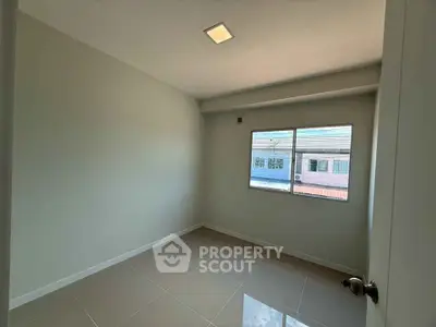 Bright empty room with tiled floor and large window, perfect for customization.