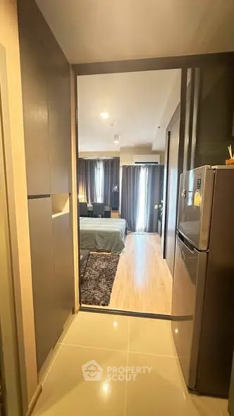 Modern apartment hallway leading to a cozy bedroom with stylish decor and natural light.