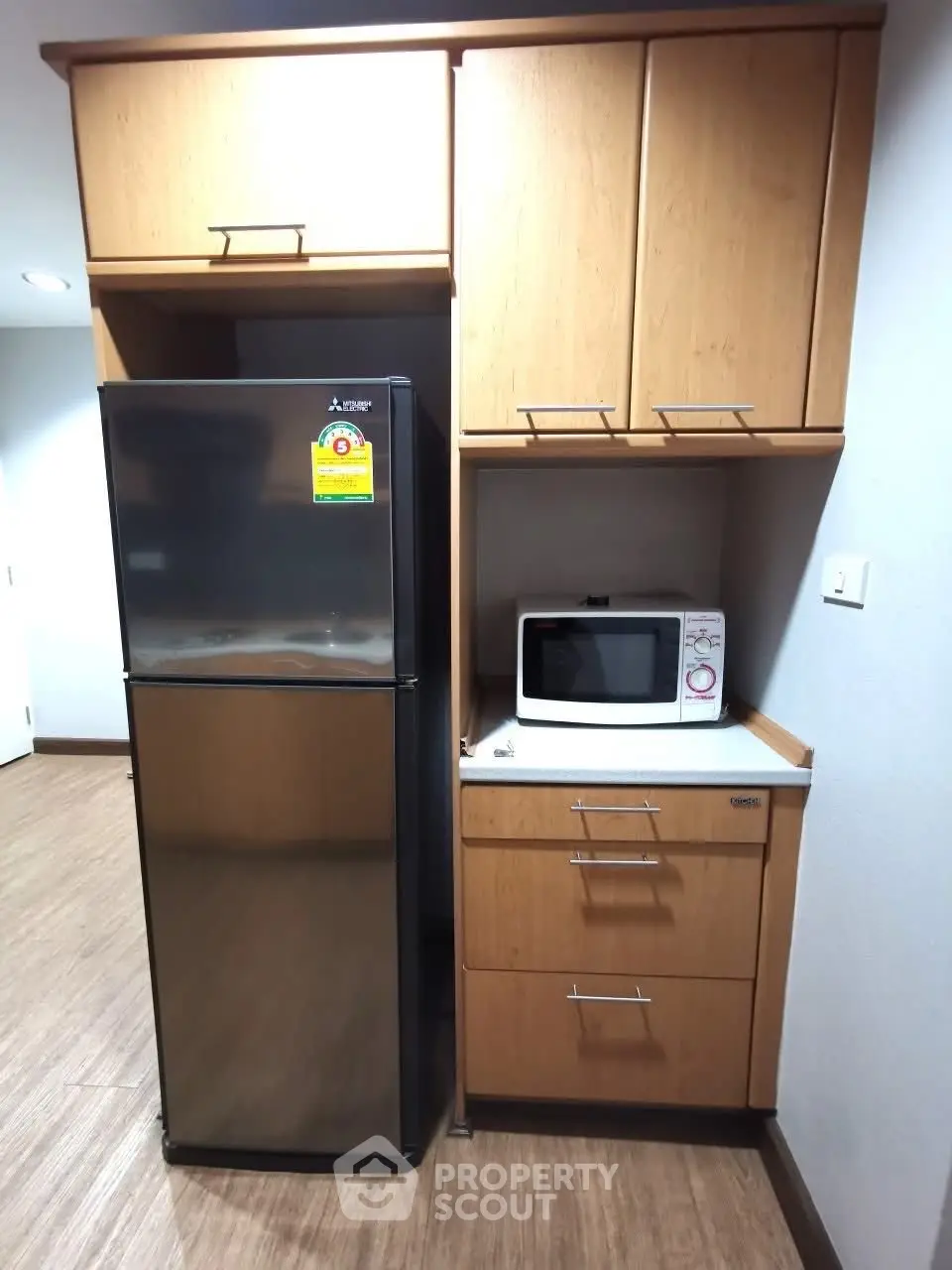 Modern kitchen with sleek fridge and microwave in stylish wooden cabinetry.