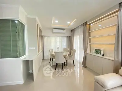 Elegant living room with modern decor and dining area, featuring large windows and stylish furniture.