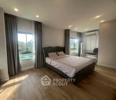 Spacious bedroom with large windows and elegant decor, featuring a comfortable bed and stylish flooring.