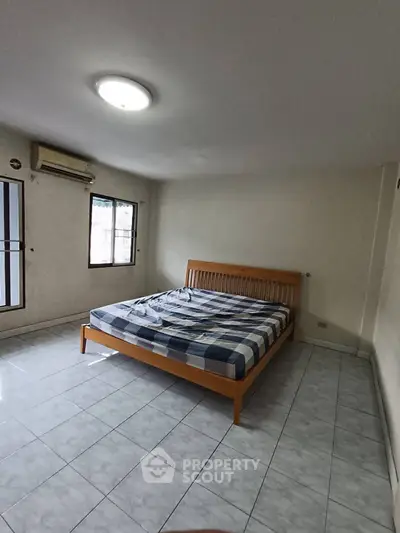 Spacious bedroom with tiled floor and large windows for natural light.