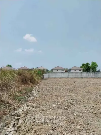 Vacant land with potential for development near residential area under clear blue sky.